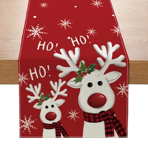 Macro detail of red linen Christmas table runner featuring white reindeer and snowflakes