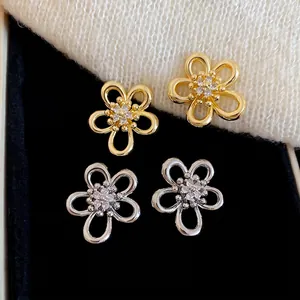 Sparkling zircon flower stud earrings in gold and silver finish on soft texture