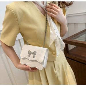 Détail du sac à bandoulière blanc texturé avec boucle métallique en forme de nœud