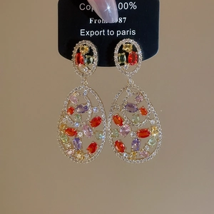 Detail of colorful hollow oval earrings with gold-plated copper and zircon inlay
