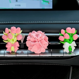 Close-up of pink tulip and hydrangea flower-shaped air vent aroma clips in car interior
