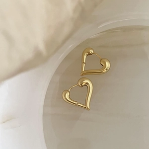 Close-up of golden heart-shaped hoop earrings on glass with a warm soft background