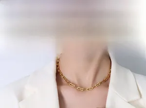 Gros plan d'un collier à maillons rectangulaires plaqué or 18k sur un mannequin en costume