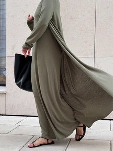 Detail of olive green knit long dress set showing fluid fabric texture in motion