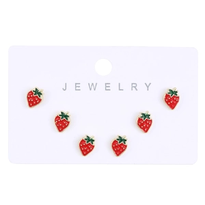 Detailed view of three pairs of red enamel strawberry stud earrings on a card