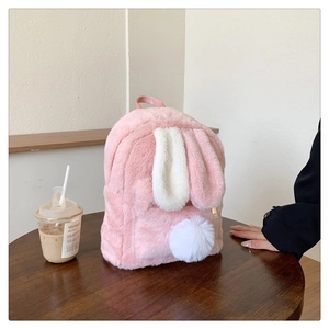 Detailed texture of pink plush backpack with white bunny ears on a wooden table