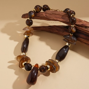 Détail de perles en acrylique vintage sur support en bois avec accents ambre et dorés