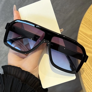Detail of oversized sunglasses with black frame and purple gradient lenses on a desk