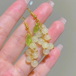 Detailed close-up of grape cluster earrings with green leaves and gold metal hooks