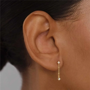 Detail of elegant gold tassel earrings featuring two brilliant white diamonds on thin chains