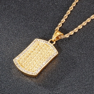 Close-up of golden rectangular dog tag pendant with woven texture and sparkling crystals