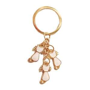 Detailed view of three white enamel cat pendants on a glossy golden metal keychain