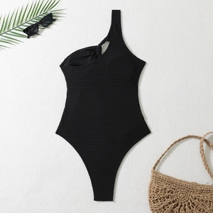 Détail d'un maillot de bain une épaule noir avec texture côtelée et bride à nœud unique