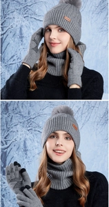 Close-up of knit beanie with pompom and touchscreen gloves in a snowy forest setting