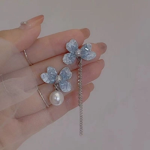 Makroansicht der blauen Kristallblumenohrringe mit Perle und langer silberner Quastenkette