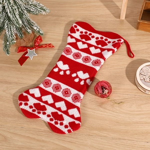 Knitted bone-shaped Christmas stocking with paw prints on festive wooden background