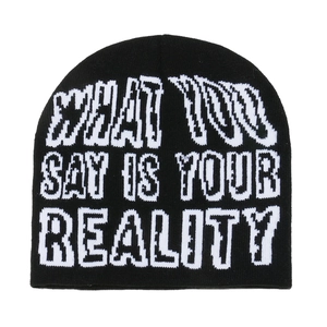 Detail of black knit beanie featuring white jacquard text WHAT YOU SAY IS YOUR REALITY