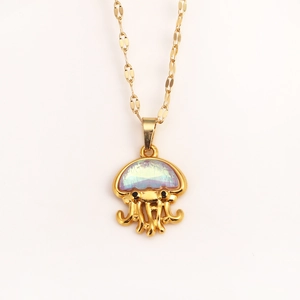 Macro shot of gold jellyfish pendant with iridescent gemstone on thin link chain