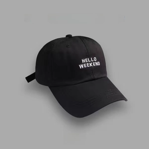 Detail of white HELLO WEEKEND embroidery on a black cotton baseball cap surface