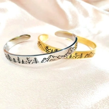 Detail of gold and silver open bangles with engraved forest and mountain scenery on silk