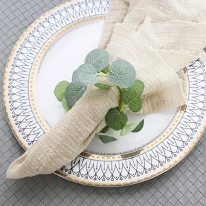 Artificial eucalyptus napkin ring on beige linen napkin with elegant white ceramic plate
