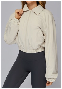 Detail of a beige zip-up sports jacket featuring a turndown collar and elastic cuffs