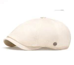 Detail of beige newsboy cap showing breathable woven texture and metal button accent