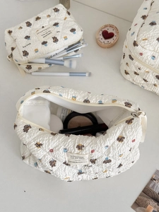 Detail of quilted beige makeup bags featuring cute brown bread dog prints and top zippers