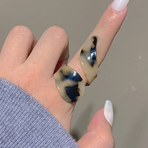 Detailed view of an irregular tortoiseshell acrylic ring on finger for vintage style