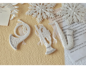 Detailed view of white glitter musical instrument ornaments with silver beads for Christmas