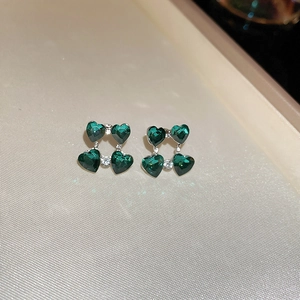 Fashionable silver studs featuring green heart-cut gemstones in a clover design