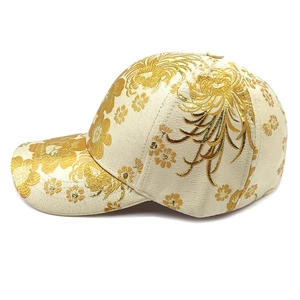 Detailed close-up of champagne satin baseball cap featuring gold floral embroidery patterns