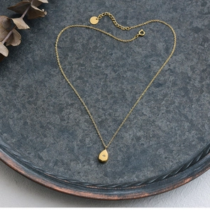 Macro shot of 18K gold plated teardrop star pendant with fine cable chain on stone tray