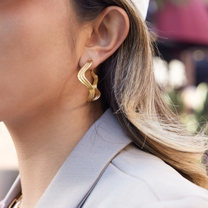 Chic 18K gold plated stainless steel wavy hoop earrings shown on a model outdoors