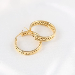 Elegant gold-tone double-layered hoop earrings with twisted woven texture on satin background