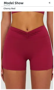 Close-up of cherry red high waist yoga shorts featuring V-cross waistband and ruching detail