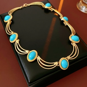 Detail of vintage gold necklace with oval turquoise gemstones on black leather display