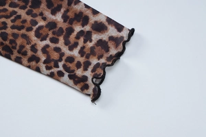Detailed macro view of the leopard print mesh fabric with elegant lettuce edge stitching