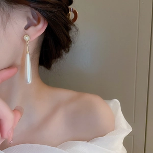 Close-up of model wearing elegant vintage drop earrings with golden studs and white pearls
