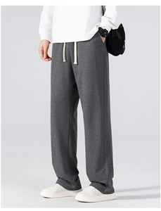 Detail of dark grey casual straight trousers showing drawstring waist and textured fabric