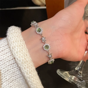 Close-up of elegant flower zircon bracelet with green gemstones on female wrist