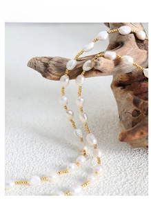 Detail of freshwater pearl necklace with gold beads draped on vintage wood branch