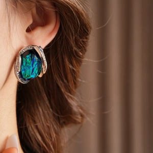 Close-up of vintage resin earring with blue-green gemstone and sparkling zircon accents