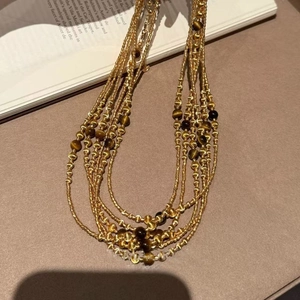 Detail of layered 18k gold plated necklace with tiger eye beads on vintage book pages