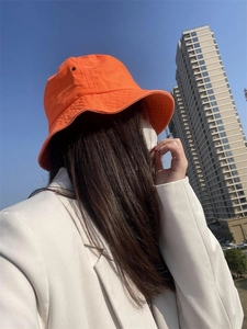 Street style view of a vibrant orange cotton sun bucket hat worn in an urban setting