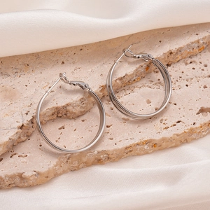 Gros plan de boucles d'oreilles doubles anneaux argentés sur texture marbrée