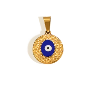 Close-up of golden evil eye pendant with hammered metal texture and blue enamel inlay