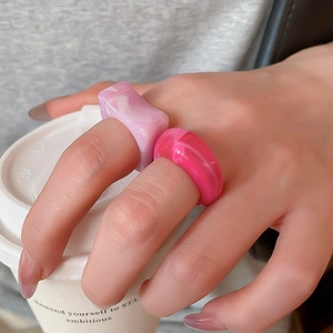 Detailed close-up of pink marbled acrylic resin square and round stackable rings set