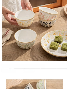 Detail of floral ceramic bowls and plates with gold rim on a wooden table