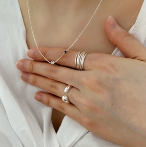 Close-up of minimalist 925 sterling silver multi-line ring and necklace on model
